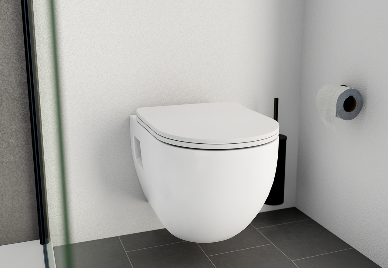 Une toilette suspendue blanche au couvercle fermé, fixée sur un mur blanc avec une brosse noire au sol et un rouleau de papier toilette. Une touche contrastée par x²o badkamers.