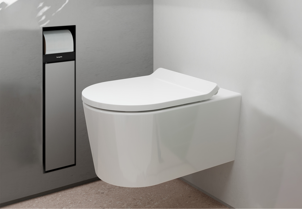 Une toilette suspendue blanche au design anguleux, montée à côté d’un distributeur de papier toilette encastré en noir et acier. Design minimaliste signé x²o badkamers.