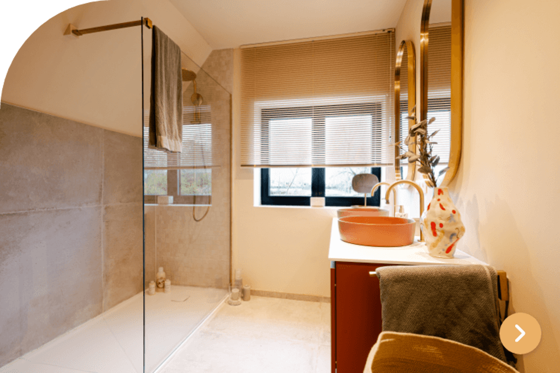 Warme badkamer met beige tegels, oranje wastafel en glazen douchewand