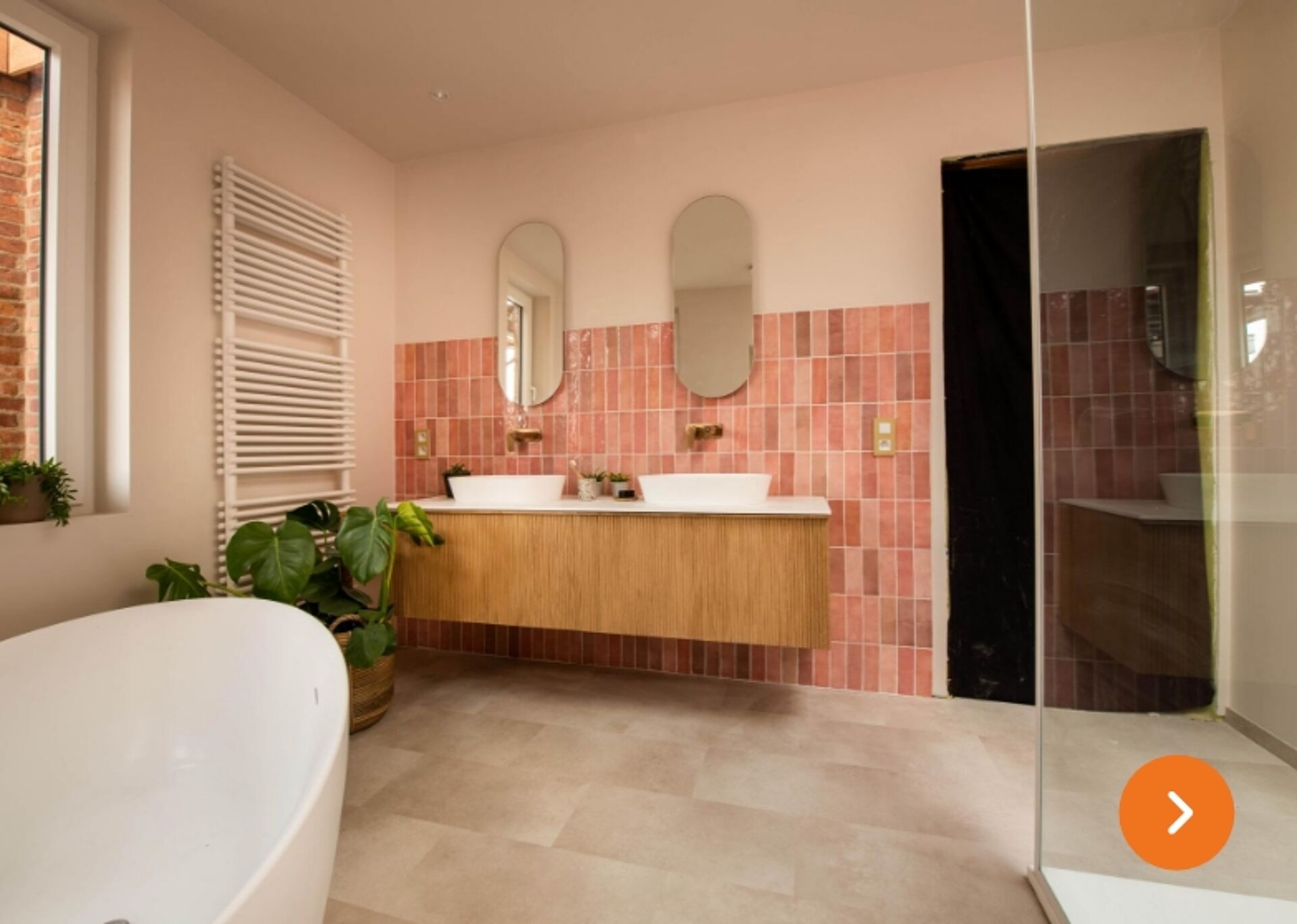 Moderne badkamer met roze wandtegels, dubbele wastafel en vrijstaand bad