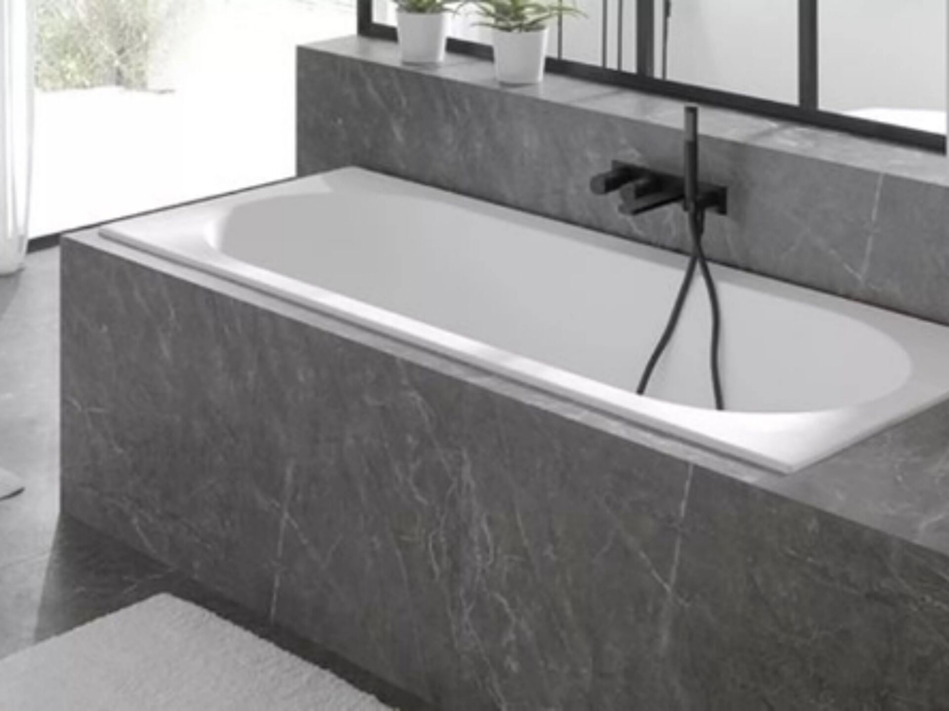 Badewanne in Marmormauer eingebaut mit schwarzem Wasserhahn.