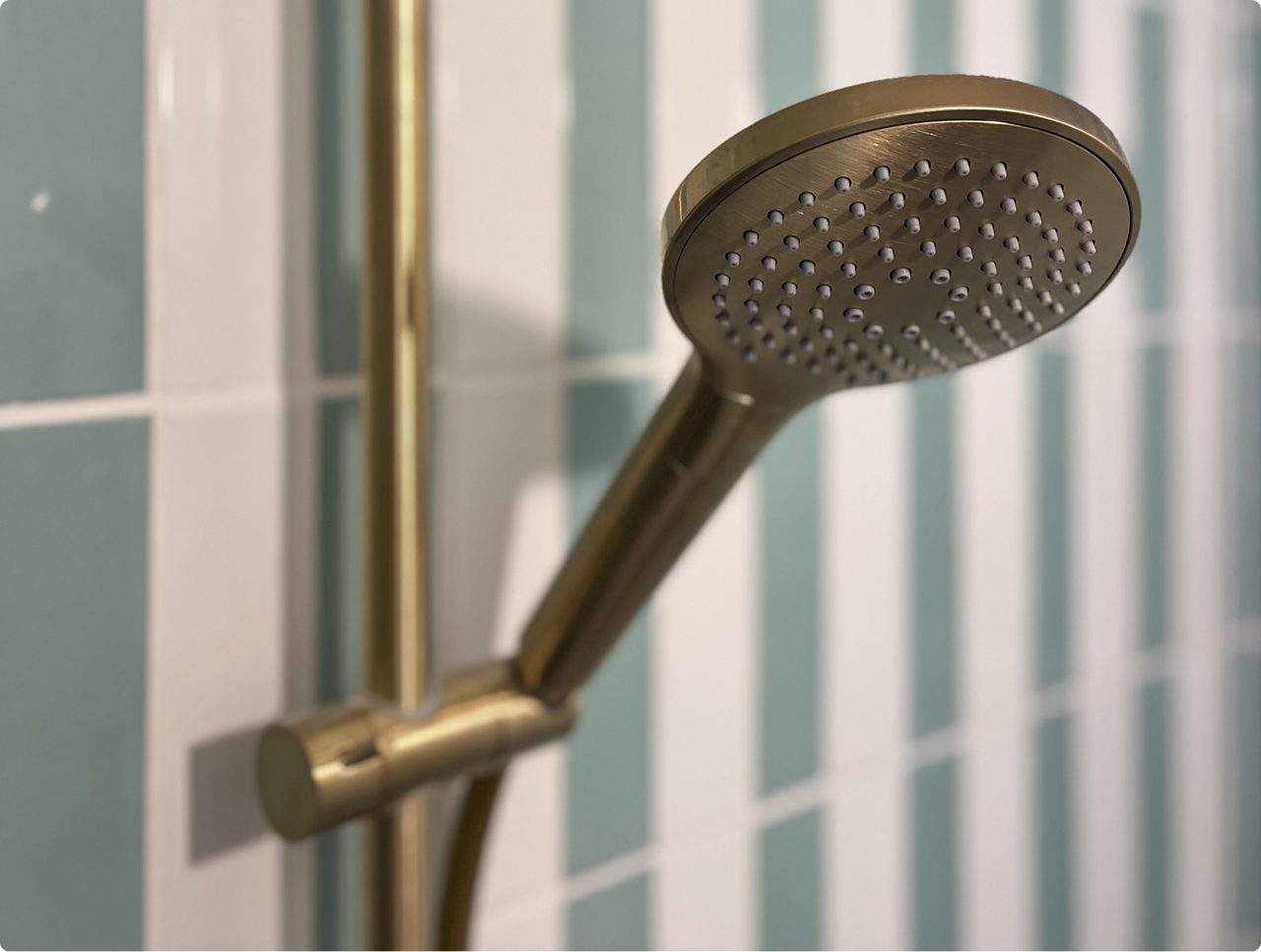 Bad-douche met gouden kraanwerk en verticale pastelgroene tegels, inclusief het vertrouwde badeendje – een creatie van x2o badkamers.