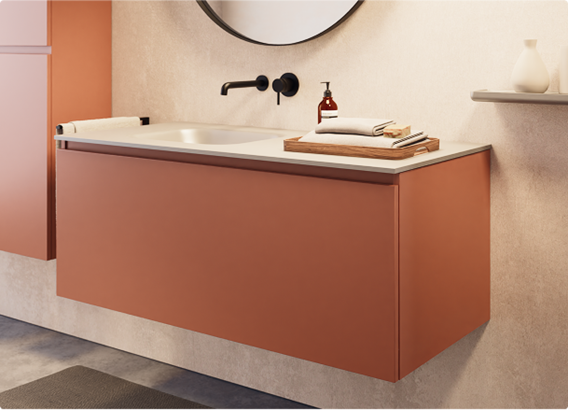 x²o Badezimmer mit warmen Farbakzenten durch matten orangenen Waschtischunterschrank, schwarze Armatur, runder Spiegel und stilvolle Accessoires an einer beigen Wand.
