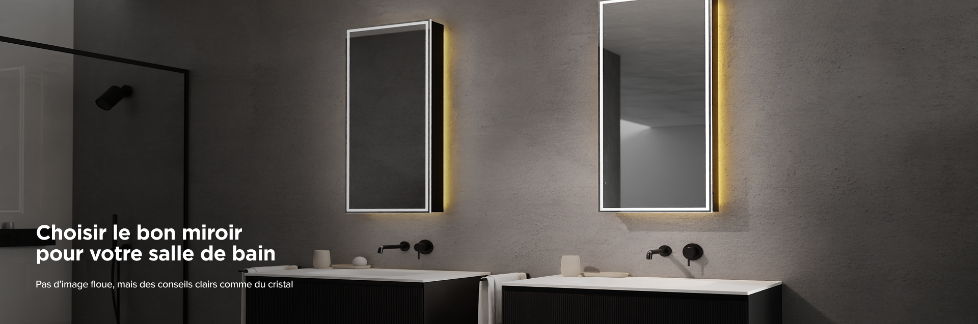 Salle de bains x²o avec deux miroirs verticaux éclairés sur un mur gris, chacun au-dessus d’un meuble lavabo noir avec vasque blanche, robinet mural noir minimaliste, accessoires beiges et une douche à l’italienne noire visible à gauche.