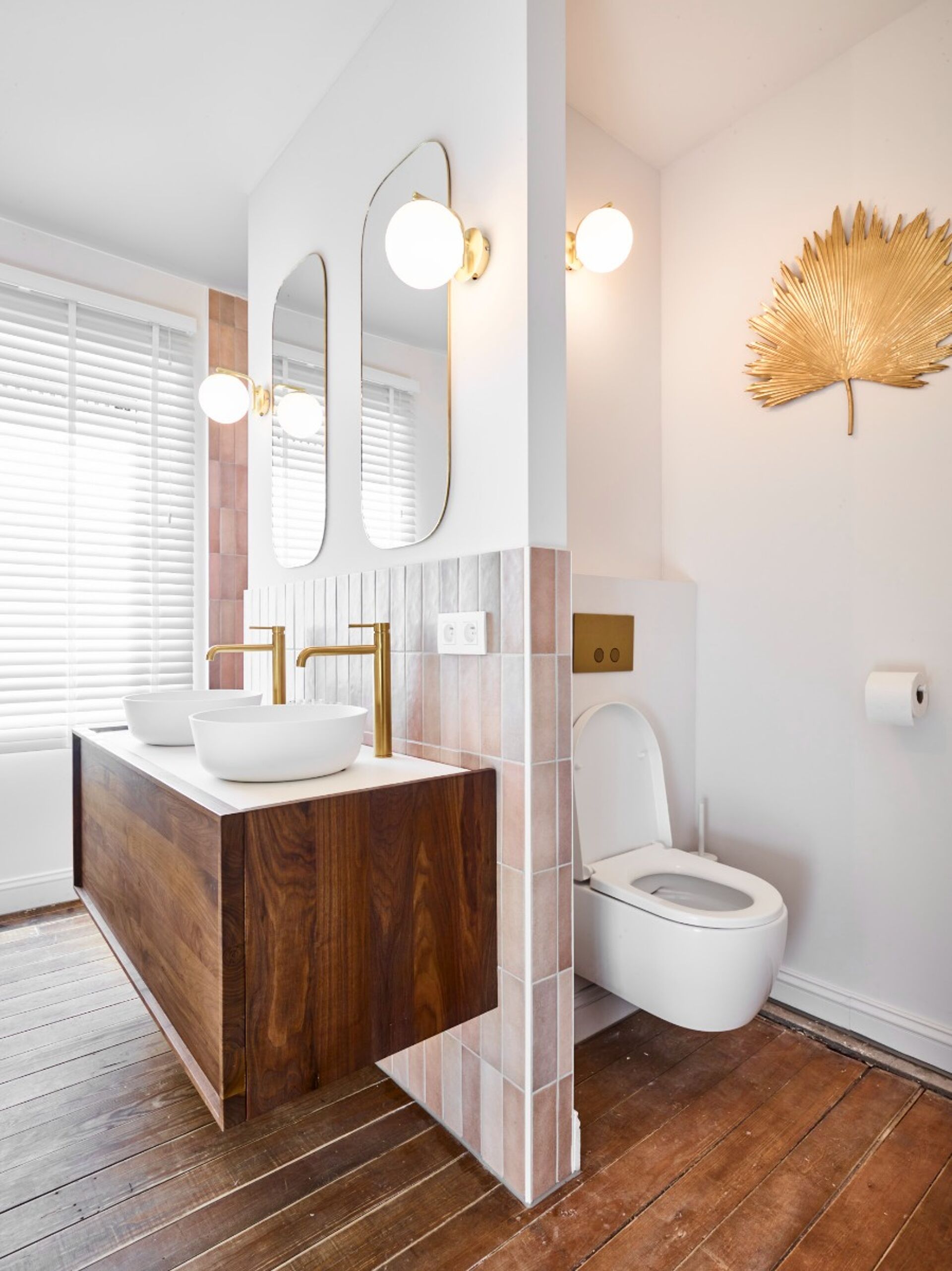 Luxuriöses Badezimmer mit Holzboden, goldenen Armaturen und Doppelwaschbecken
