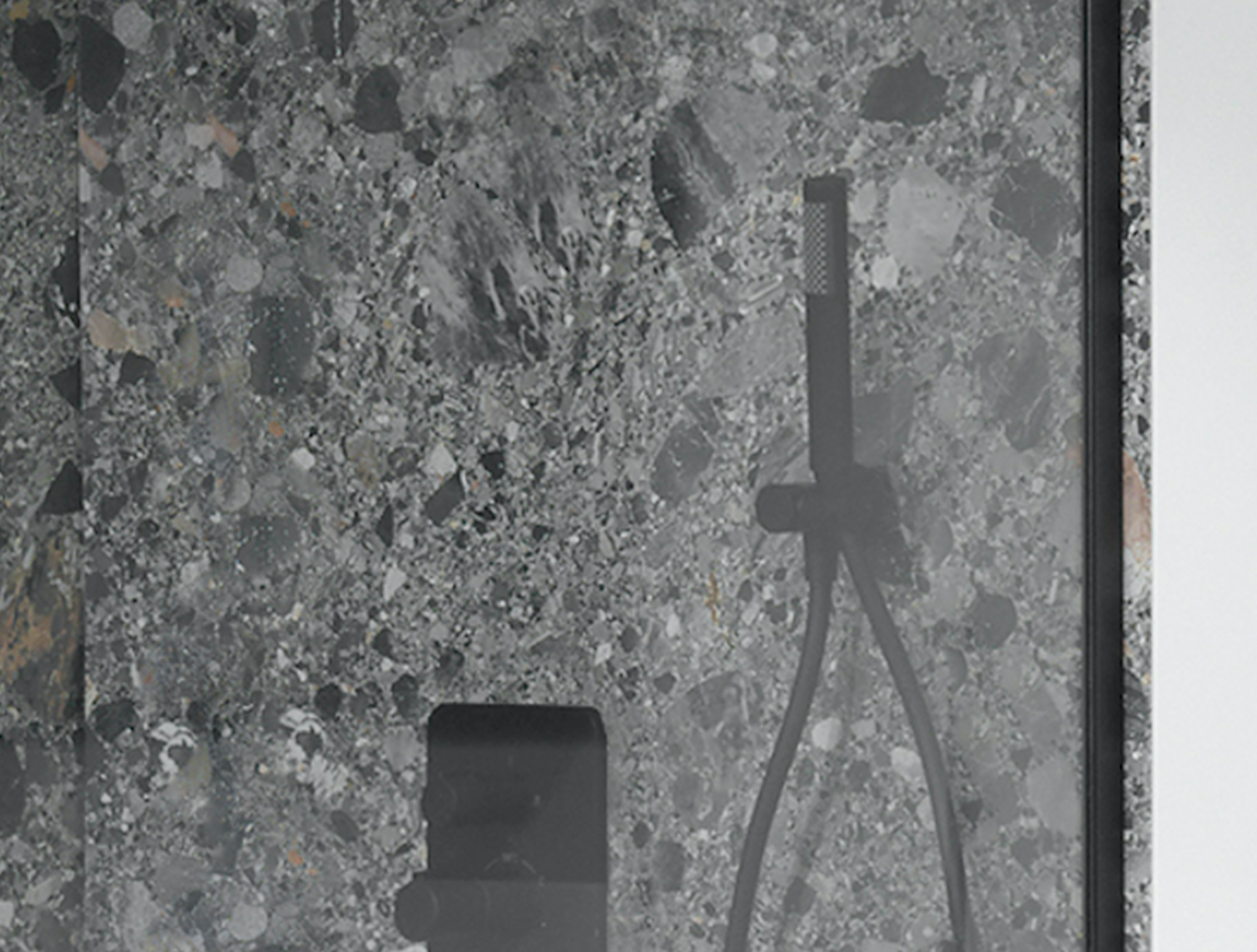 Luxuriöse Duschwand in Marmoroptik mit integrierter schwarzer Handbrause und Thermostatarmatur.