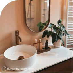 Moderne badkamer met ronde waskom, bronzen kraan en houten details voor een warme en natuurlijke uitstraling.