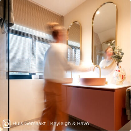 Moderne badkamer met roze wastafelmeubel, ronde waskom en gouden accenten voor een warme uitstraling.