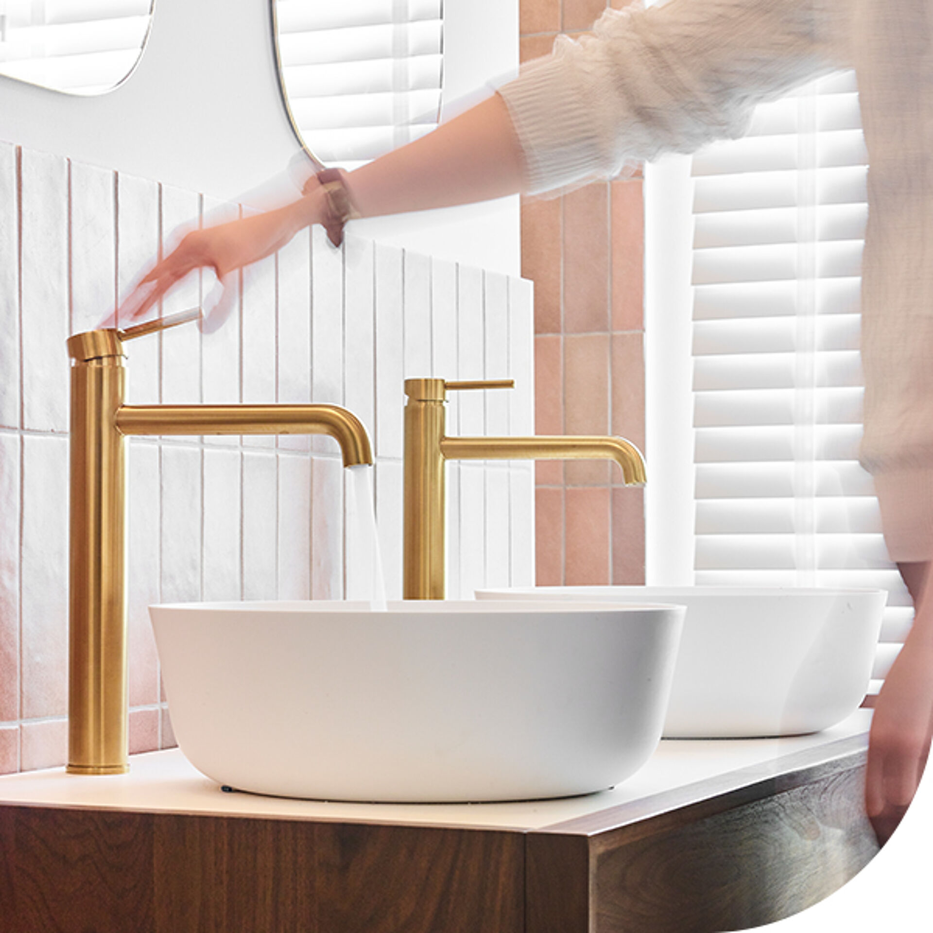 Doppelte weiße Waschbecken mit goldenen Armaturen und moderne Badezimmerwand mit weißen Fliesen.