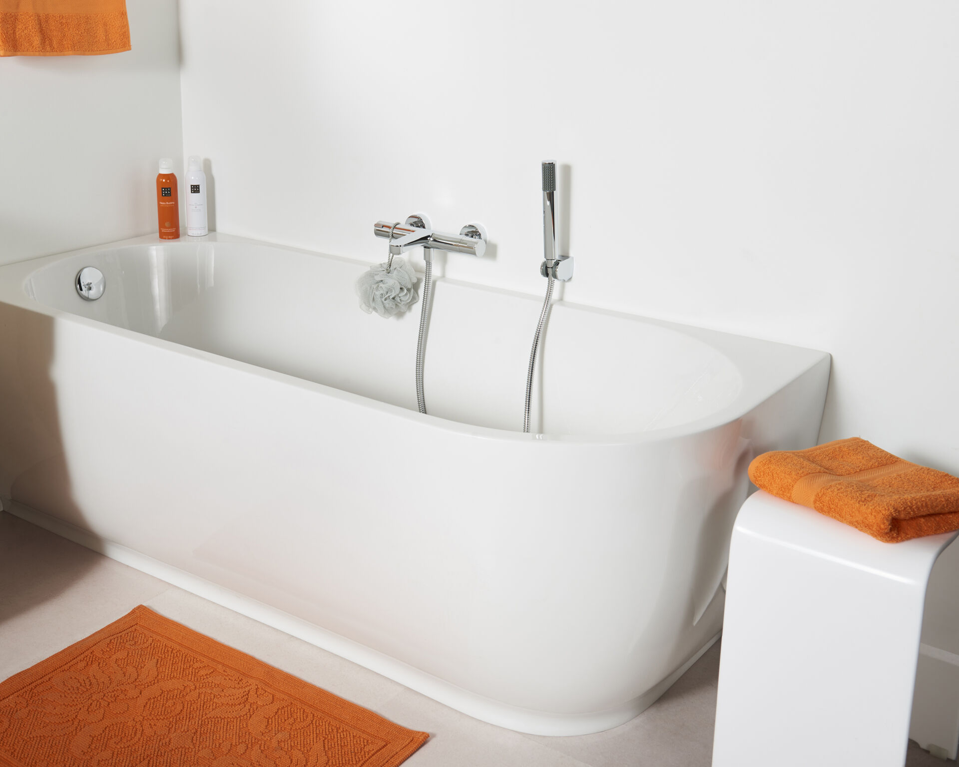 Badewanne mit Duschkopf, orange Handtüchern und modernem, minimalistischem Design.