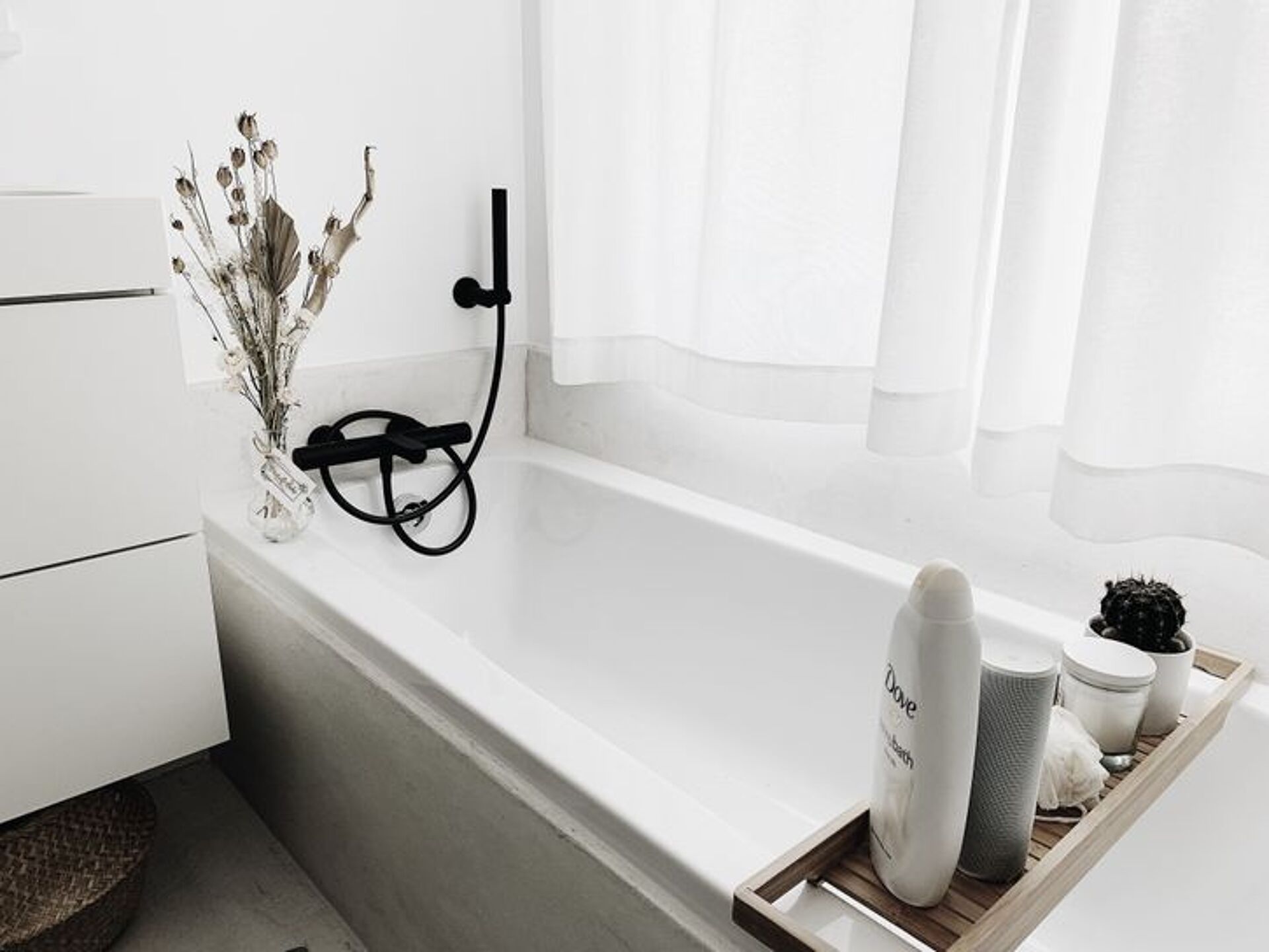Moderne badkamer met witte badkuip, zwart kraan en verzorgingsproducten