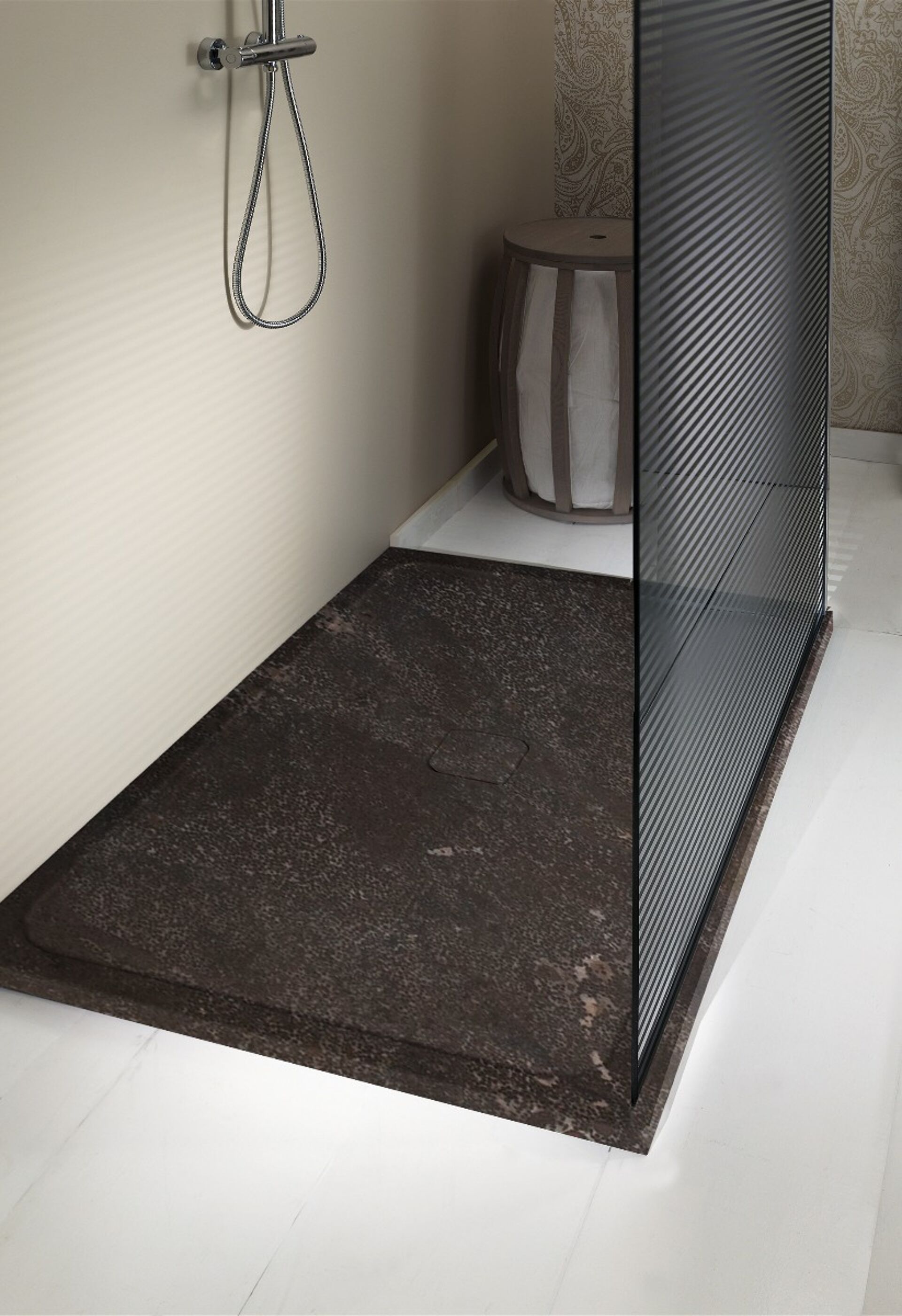 Moderne Dusche mit einem dunkelbraunen Steinboden und einer Glaswand. Es gibt einen versteckten Abfluss und einen grauweißen Stuhl