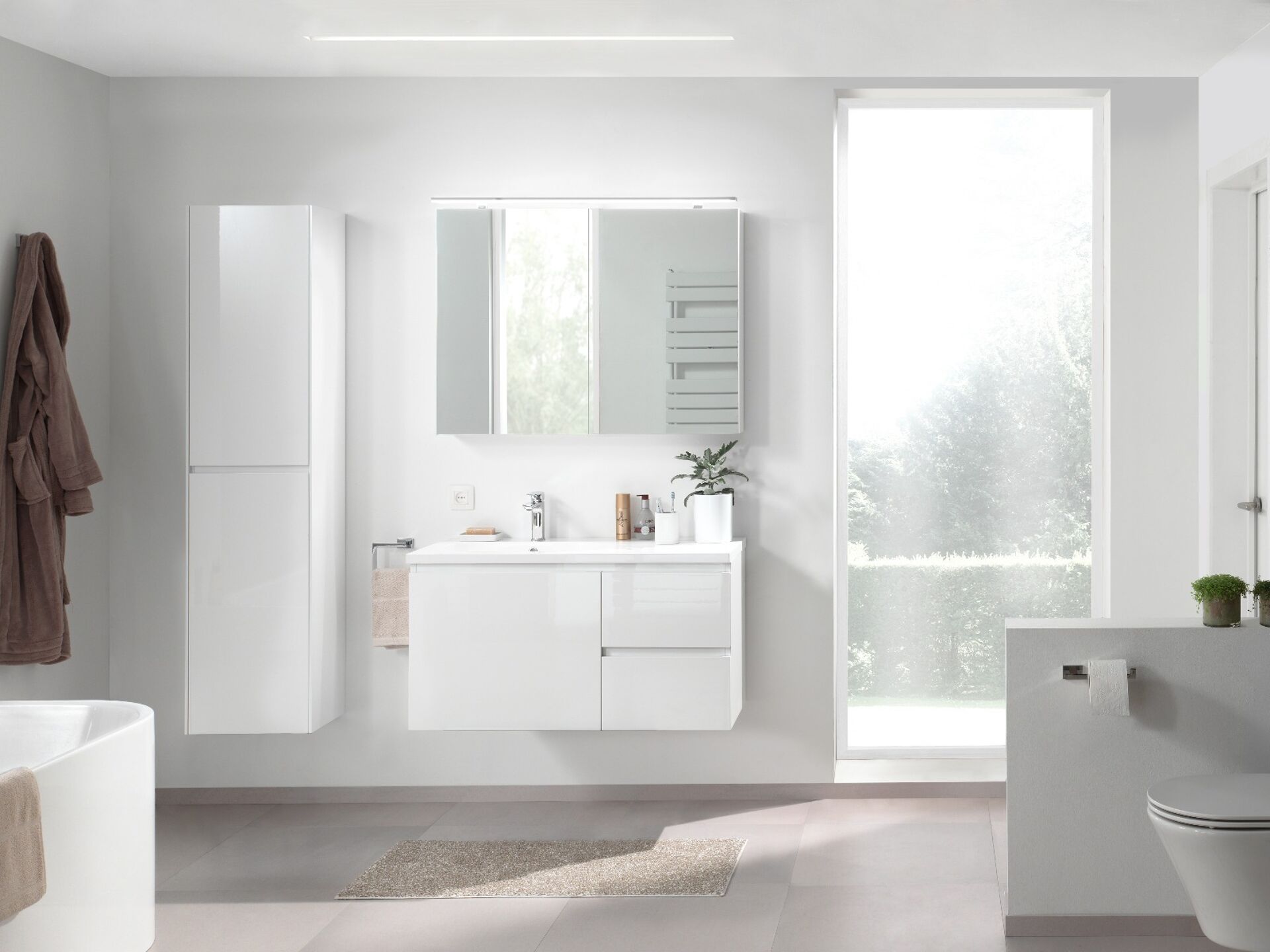 Moderne Badezimmer mit einem weißen Badmöbel, Spiegel, Handtuchhalter, Pflanze und Toilette, beleuchtet von natürlichem Licht