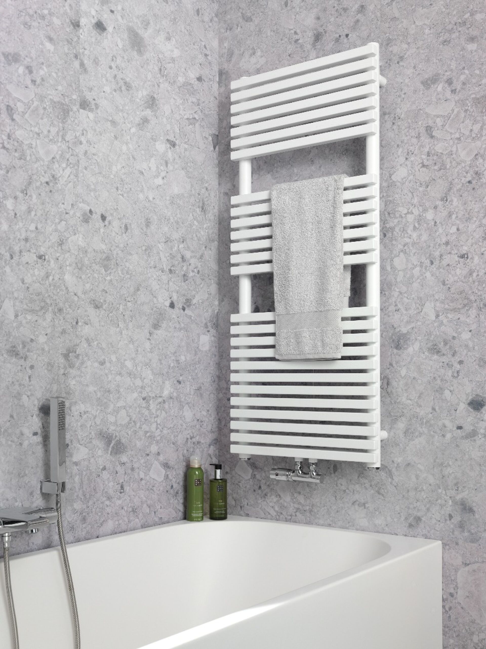 Modernes Badezimmer mit einer Badewanne, weißem Handtuchheizkörper und Marmormauer, mit einem Handtuch und Duschflaschen.