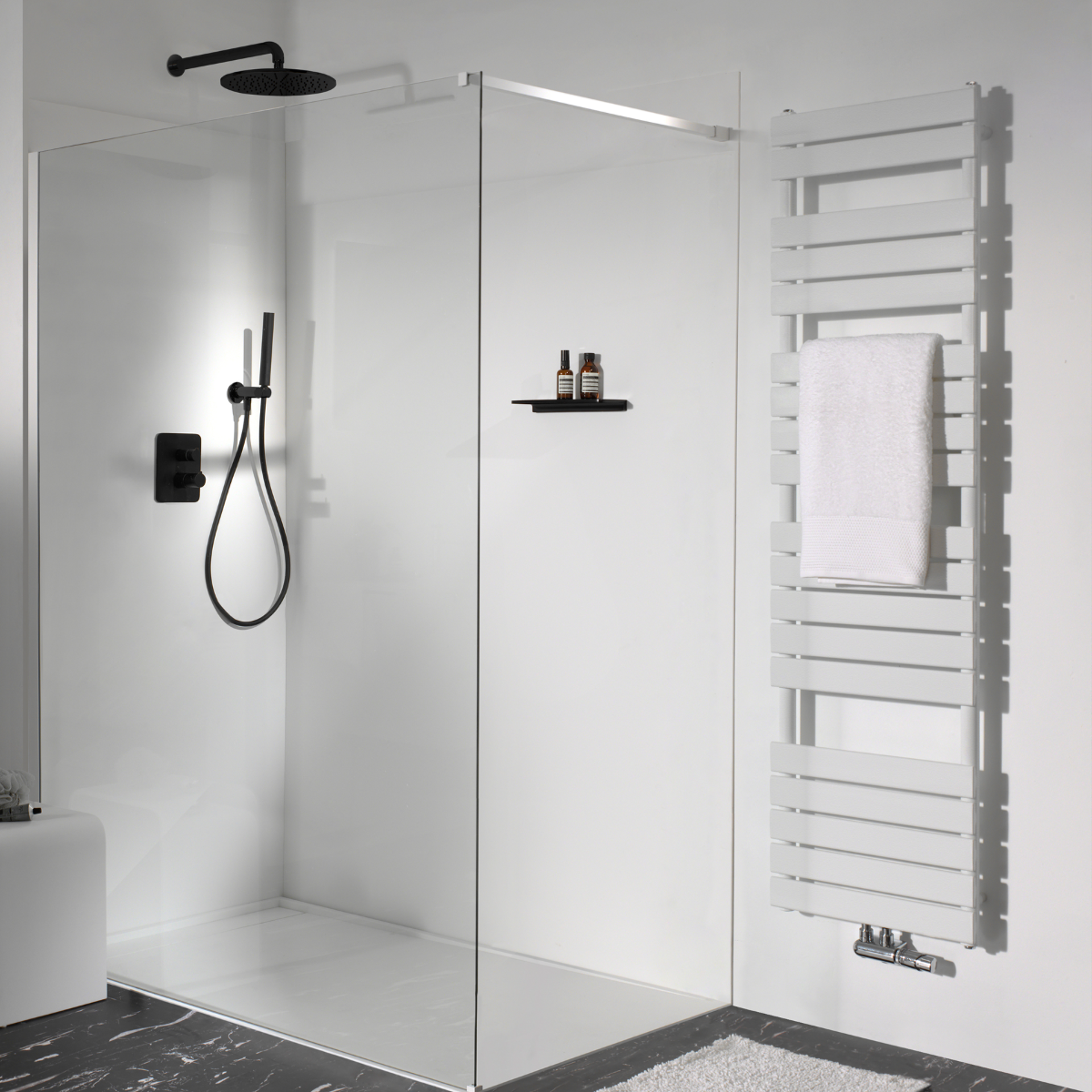 Moderne Dusche mit Glaswand, schwarzem Duschkopf, Handbrause, weißem Handtuchheizkörper und Regal mit Duschprodukten