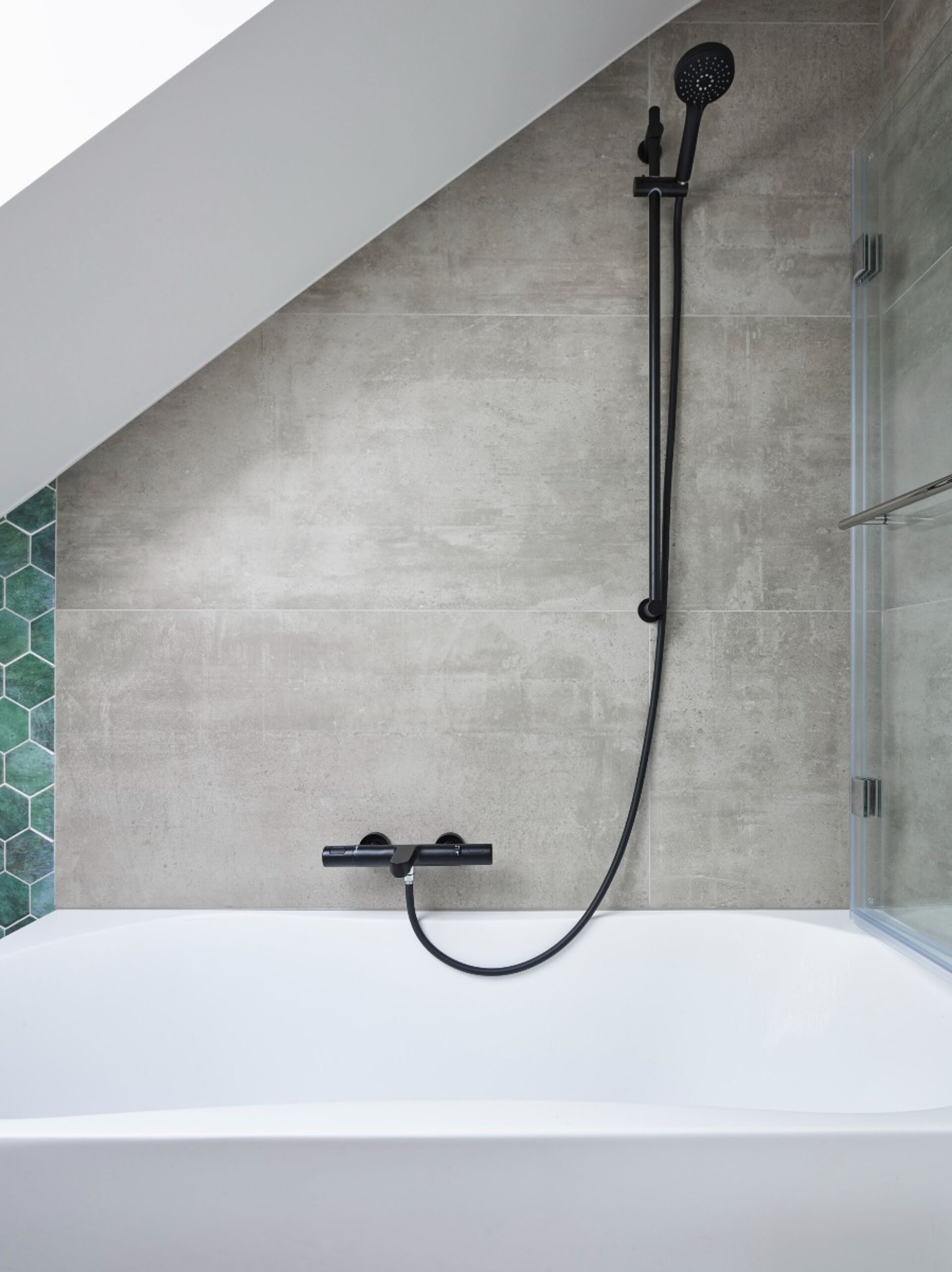 Badezimmer mit freistehender Badewanne, schwarzem Regenduschkopf und grünen hexagonalen Fliesen
