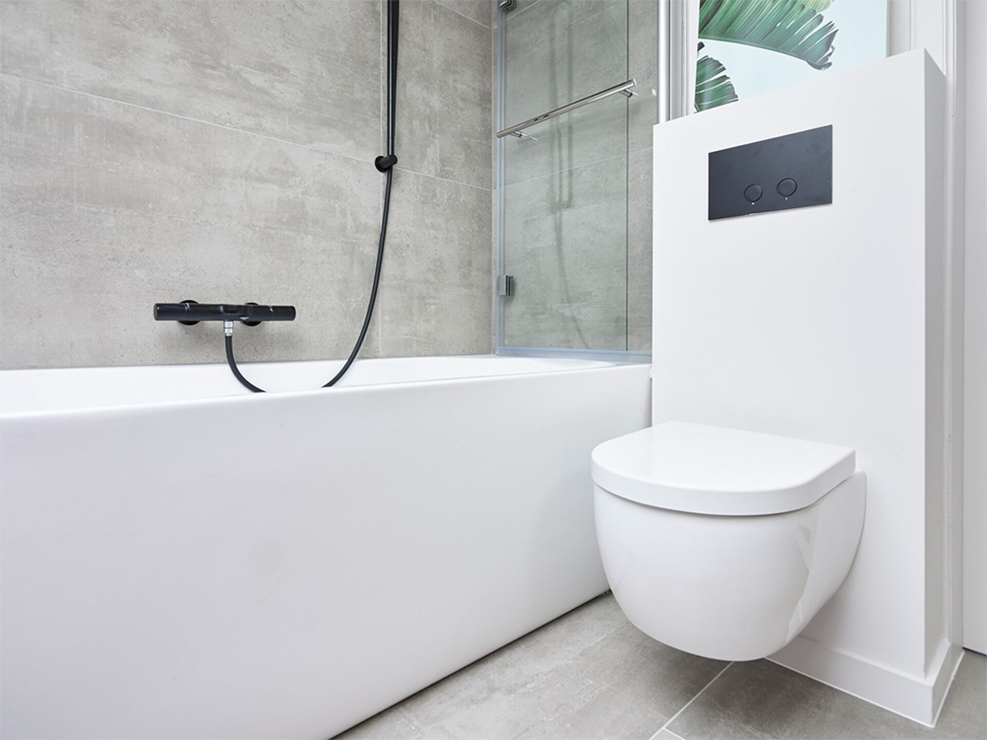 Weißes Bad, schwarzer Wasserhahn, Dusche mit Glaswand und wandhängendes WC.
