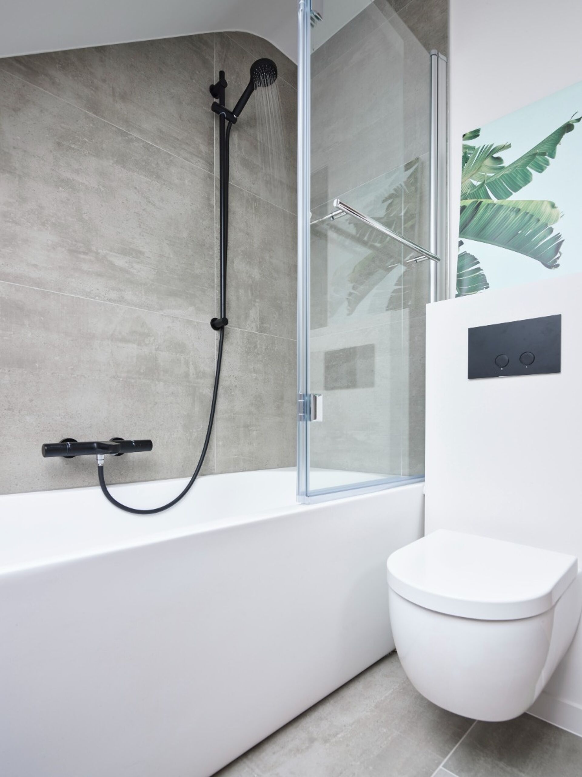 Weißes Badezimmer mit Badewanne und schwarzer Regendusche mit Glaswand.
