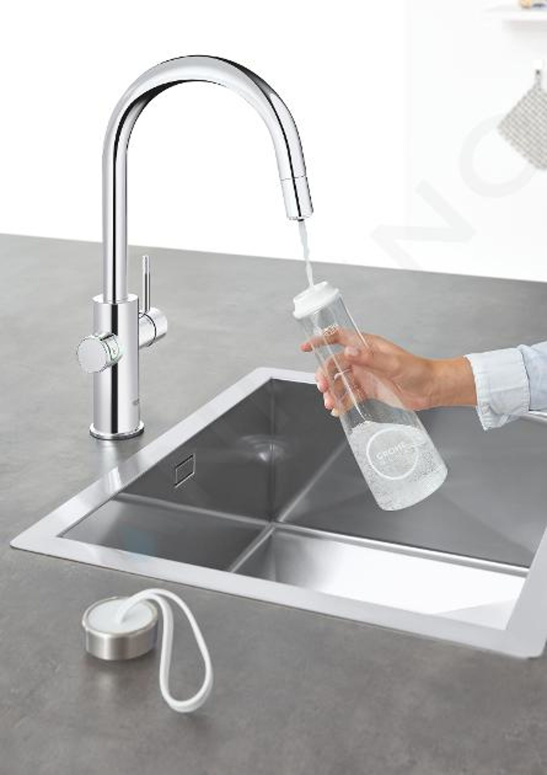 Küchenarmatur mit einer Wasserflasche, die in einem Edelstahlspülbecken gefüllt wird.