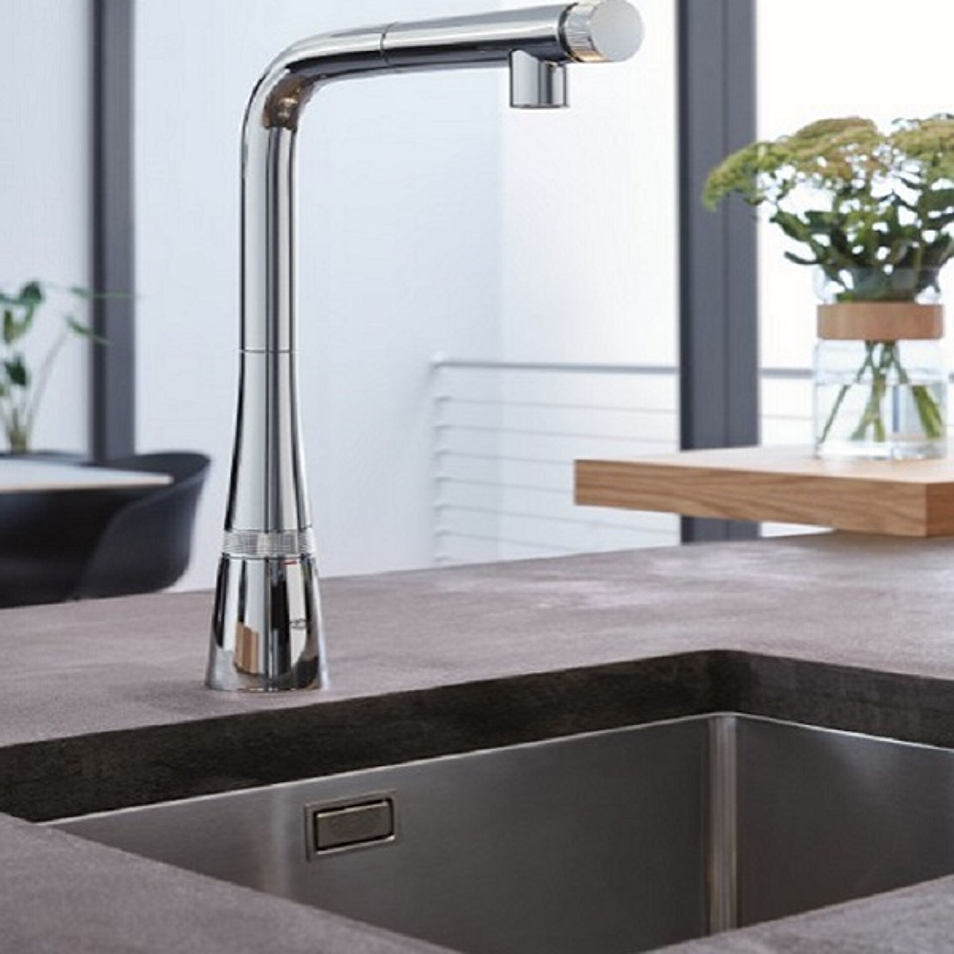 Küchenarmatur über einem Edelstahlspülbecken mit modernem Design und verchromter Oberfläche.