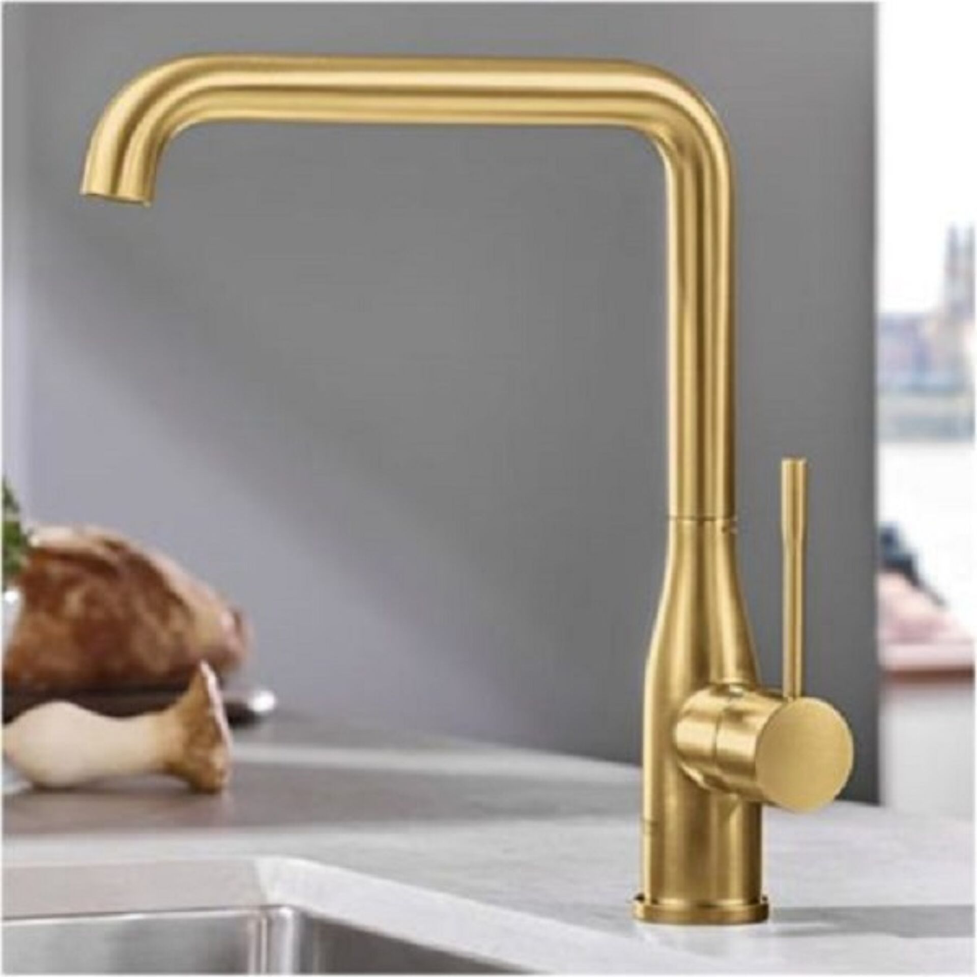 Goldene Küchenarmatur mit modernem Design und seitlichem Hebel.