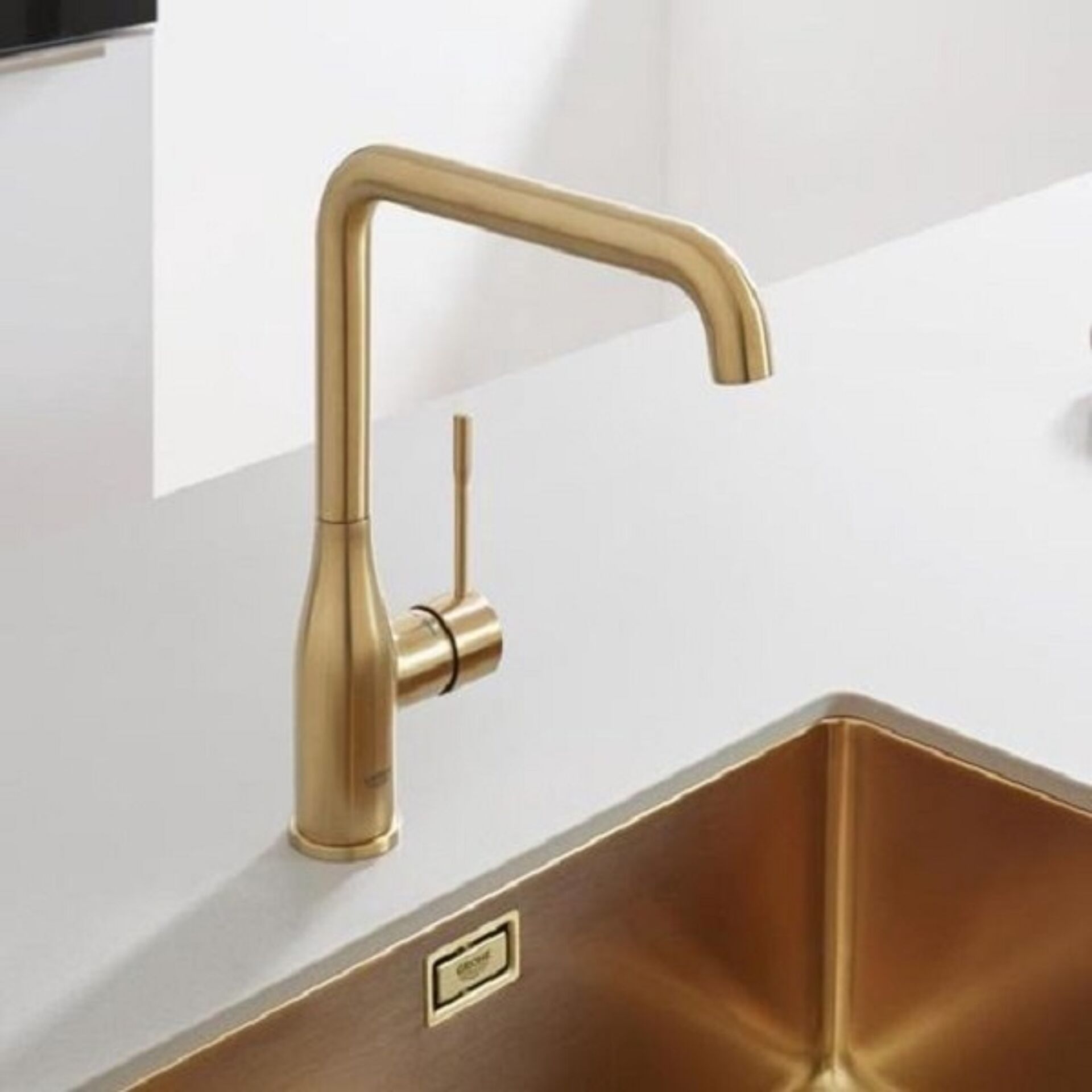 Küchenspüle in goldfarbenem Metall mit modernem geraden Auslauf und Steuerhebel.