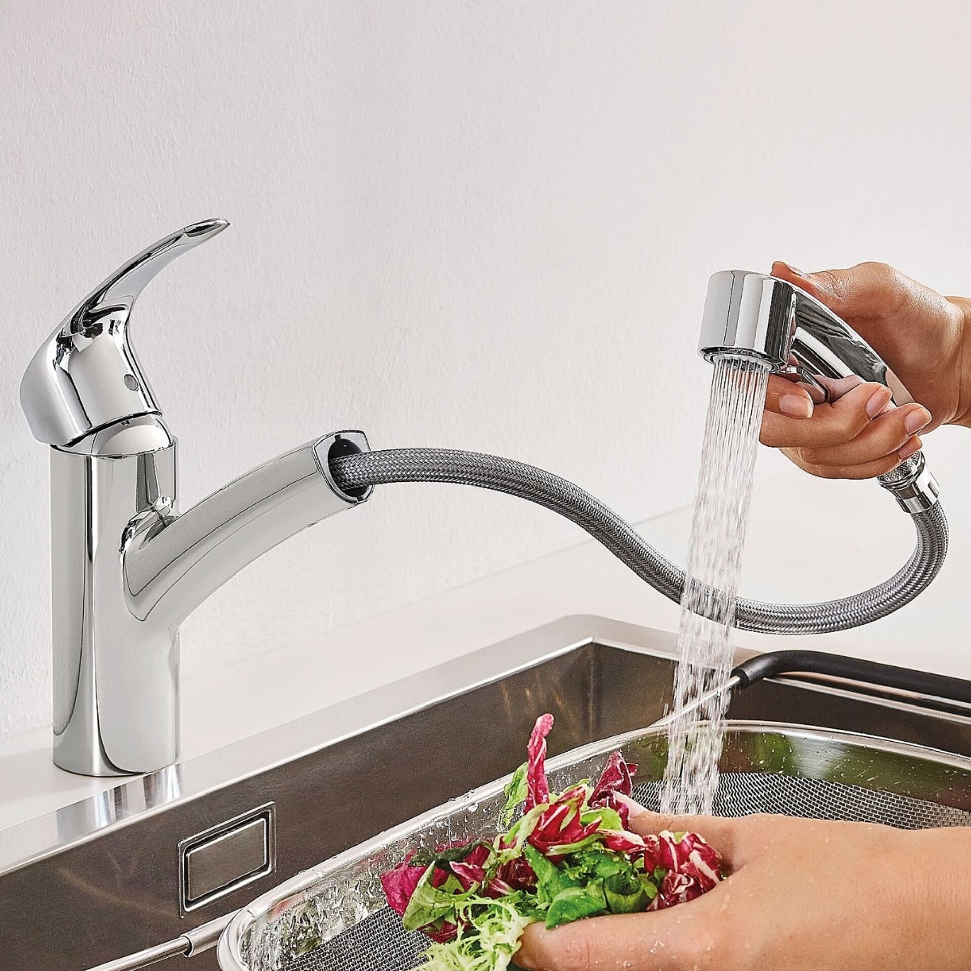 Robinet de cuisine chromé avec douchette extractible, utilisé pour laver des légumes.