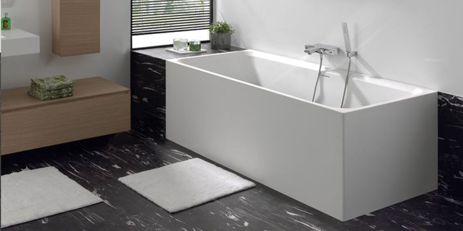 Elegante, weiße freistehende Badewanne mit modernem Wasserhahn auf schwarzem Marmorboden.
