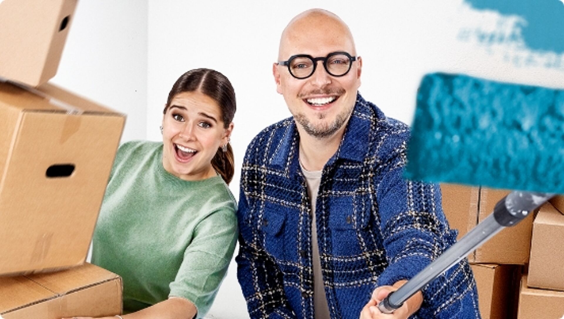 Blij duo met verhuisdozen en verfroller bezig met verhuizen of renoveren